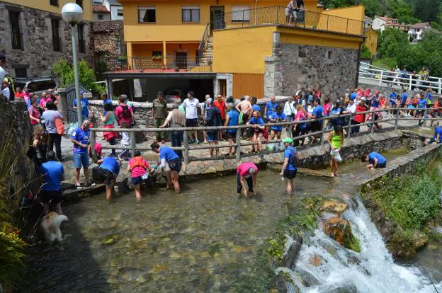 Arriba, los participantes salen del Alto de La Farrapona. Al lado, el equipo asturiano corea el himno regional en la salida. Sobre estas líneas, los corredores se limpian el barro en el río, en Pola de Somiedo. 