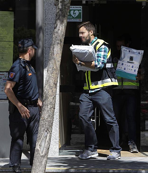 Un agente del Cuerpo Nacional de Policía se lleva material requisado ayer en el Ayuntamiento de Torrelodones (Madrid). 