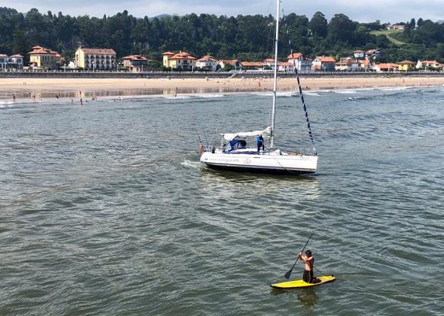 El tripulante se desplaza en la tabla para amarrar el velero. 