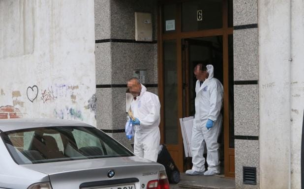Agentes de la Policía Científica salen del portal tras inspeccionar la vivienda donde se cometió el crimen