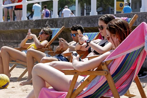 Un grupo de chavales, en la playa de Gijón, con sus teléfonos móviles. :: HUGO ÁLVAREZ