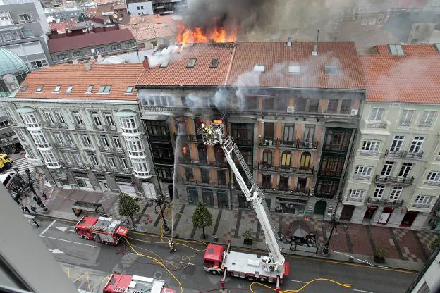 Los bomberos durante las labores de extinción del incendio que devoró el edificio número 58 de la calle Uría. 