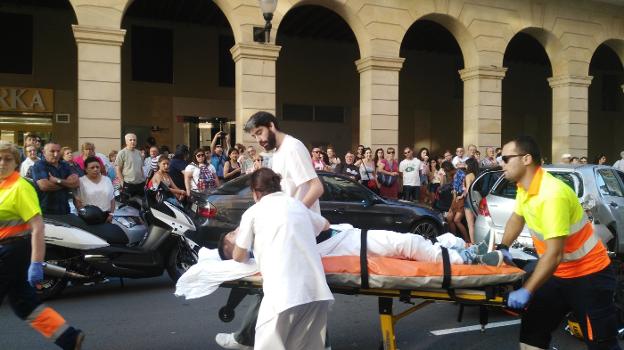 Los sanitarios trasladan al motorista herido en la calle de Marqués de San Esteban. 