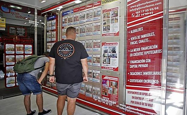 Dos ciudadanos consultan las viviendas disponibles en una inmobiliaria gijonesa. 