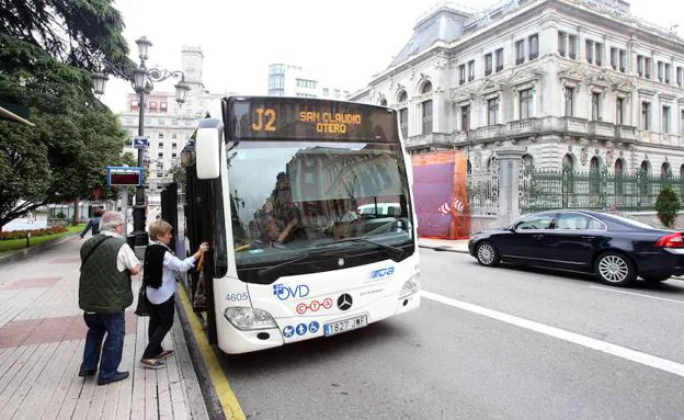 Dos personas suben a un autobús municipal en Oviedo.