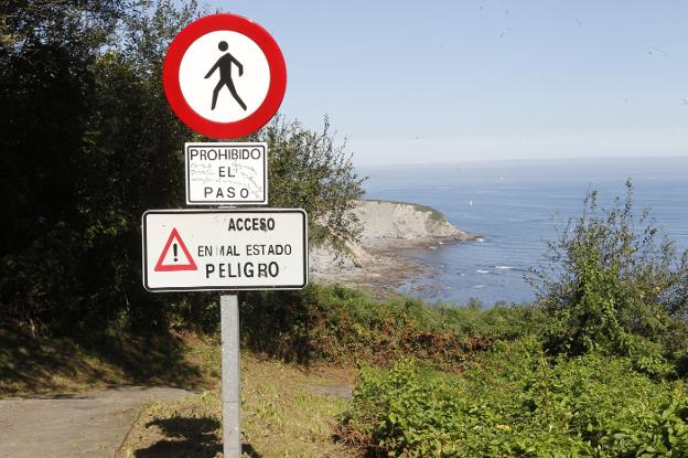 Varias señales advierten de la prohibición y del mal estado del acceso a la playa. 
