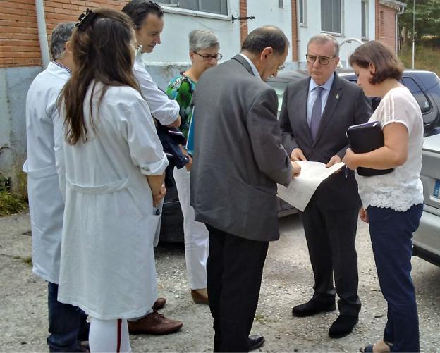 El jefe de obras de la consejería, Jesús Menéndez, explica los planos de la reforma en Tormaleo al consejero y a la alcaldesa de Ibias. 