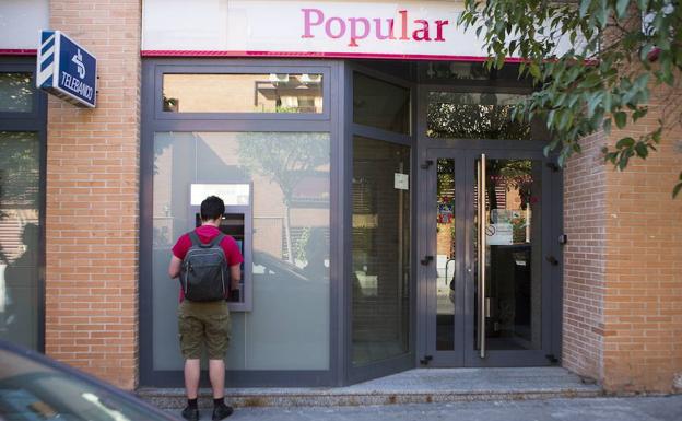 Clientes sacan dinero del cajero de una oficina del Banco Popular en Madrid. 