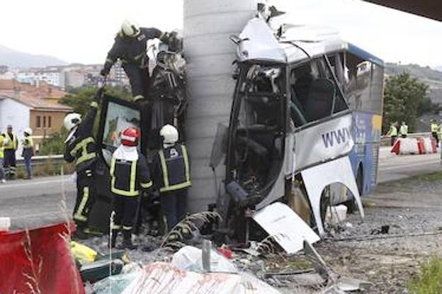 Varios bomberos trabajan sobre los restos del autobús accidentado, que cubría la línea Cudillero-Avilés-Gijón.