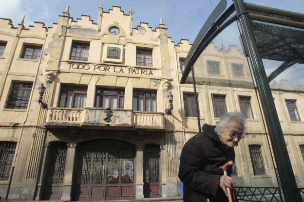 Una anciana camina por delante de la fábrica de armas de Trubia. 