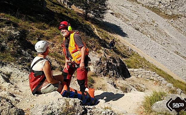 La mujer, con la pierna inmovilizada, espera por el helicóptero que la evacuó.