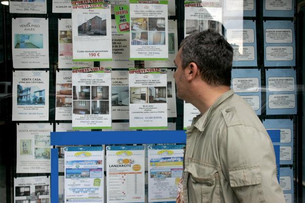 Un hombre observa los carteles de una agencia inmobiliaria. 