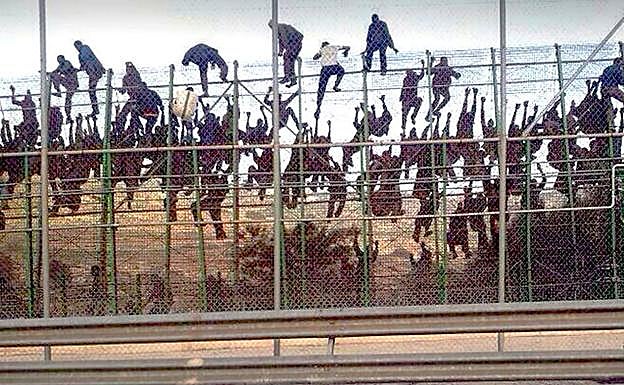 Decenas de inmigrantes escalando la valla de Melilla.
