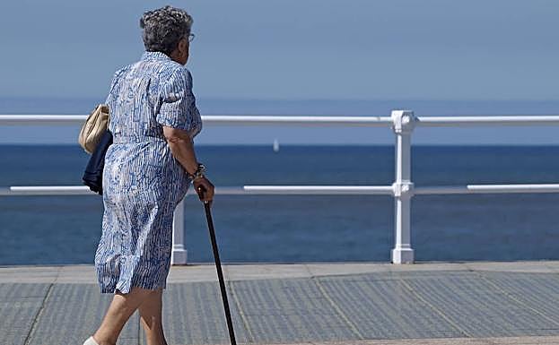 Una anciana camina por el paseo marítimo de una ciudad española. 