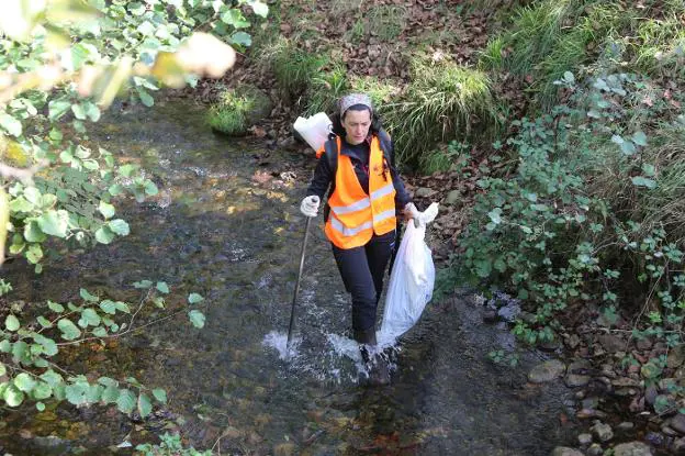 Una trabajadora de Aguas de Avilés limpiando el río. 