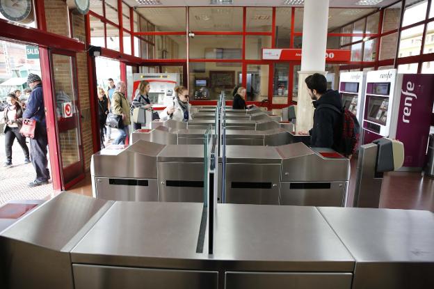 Pasajeros de cercanías, pasando los tornos con el billete. 