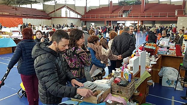 Unos compradores ojean CDs y otros artículos en el mercado. 