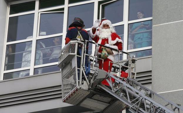 Papá Noel, en la plataforma elevadora que lo encaramó a la ventana de la planta de Pediatría. 