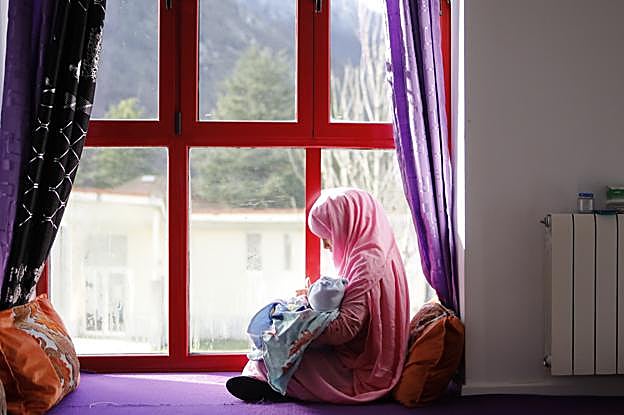 Abba, con su hijo de 24 días, aprovecha los rayos del sol que entran por la ventana para calentarse. 