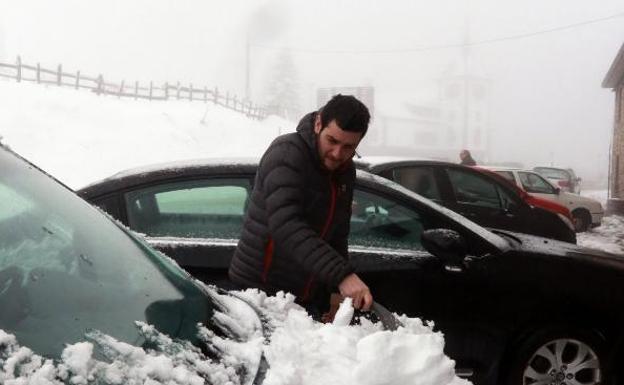 David de la Riva limpia la nieve de su coche en Pajares. 
