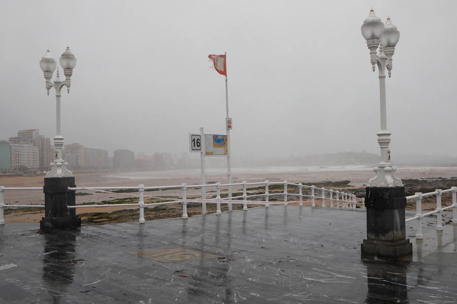 El paseo gijonés del Muro ha amanecido con algunas de sus escaleras cerradas debido a los daños causados por el temporal de lluvia y viento. Operarios de Emulsa han procedido a la limpieza de la arena depositada en el paseo tras la pleamar.