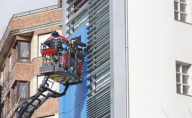 Los bomberos, trabajando en la fachada de Gijón. 