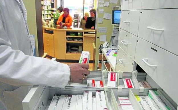 Un farmacéutico recoge una caja de antibióticos. 