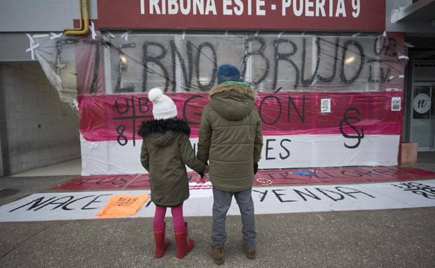 Inolvidable. Dos niños observan emocionados el improvisado mural que se montó en El Molinón tras el fallecimiento del mito. :: hugo Álvarez