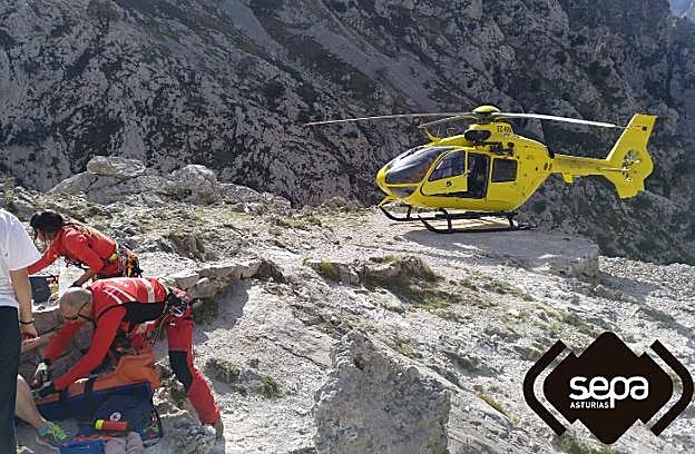Los rescatadores atienden a la senderista en plena ruta del Cares mientras el helicóptero aguarda para evacuarla. 