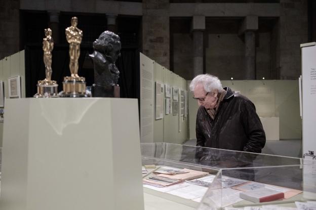 El director de cine Jaime Chávarri observa el contenido de una de las vitrinas ante los dos Oscars y uno de los Goyas de Parrondo. 