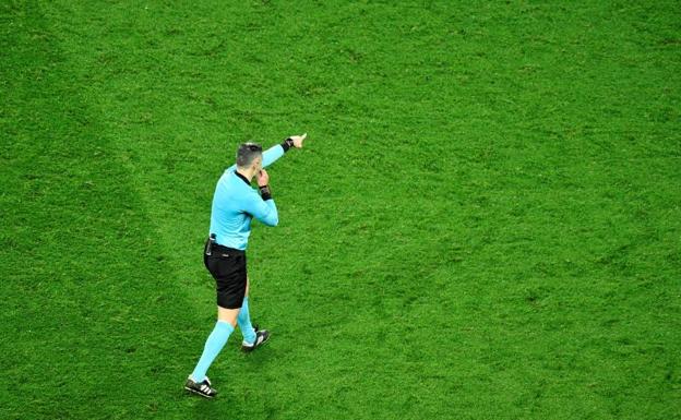 Un árbitro señala el punto de penalti. 