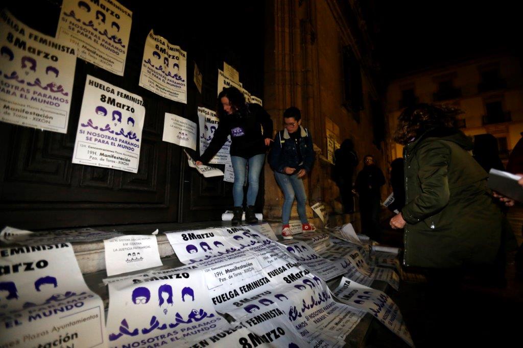 Un veintena de personas comenzó la jornada de huelga general feminista con una pega de carteles convocando a la manifestación de esta tarde en Gijón