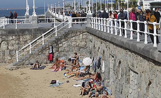 Un grupo de personas toma el sol en la playa de San Lorenzo, este sábado.