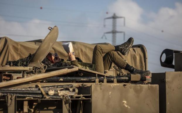 Una soldado israelí lee sobre un blindado desplegado en la verja con Gaza.