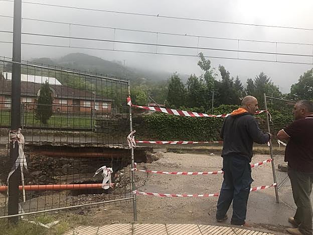 Vecinos de la zona, junto al derrumbe producido por las fuertes lluvias en febrero. 