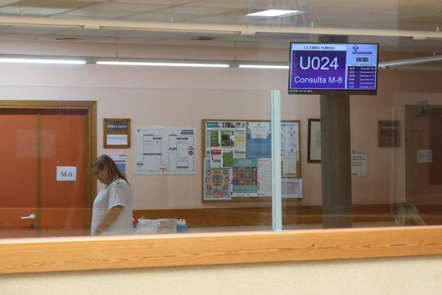 Una paciente espera ser llamada en pantalla para acudir a la consulta de su médico en el centro de salud. 