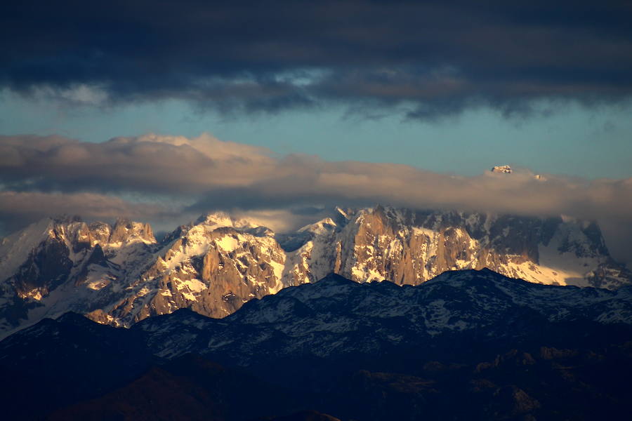 Los últimos rayos de sol iluminan la mole caliza de los Picos de Europa mientras negros nubarrones amenazan tormenta.