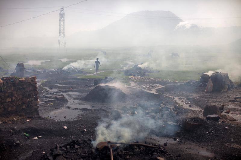 Un hombre camina junto a un montón de carbón quemado destinado al uso doméstico en Jharkhand.