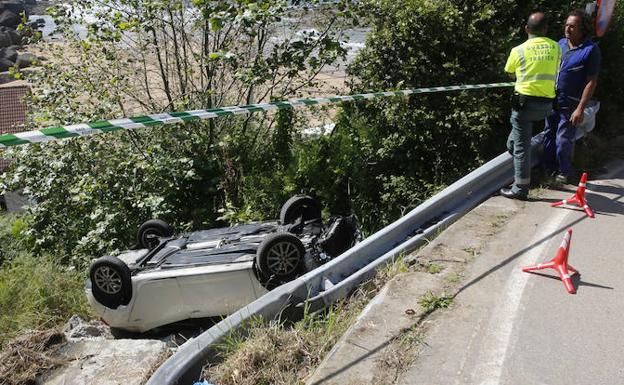 El coche, volcado en la carretera de la playa.