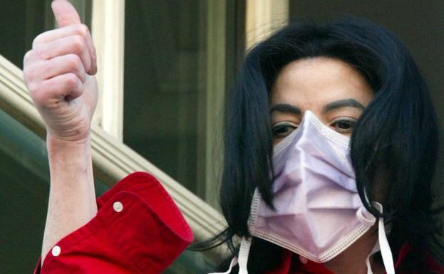 Jackson, cubierto por una máscara, saluda a sus seguidores desde un hotel de Berlín en 2002