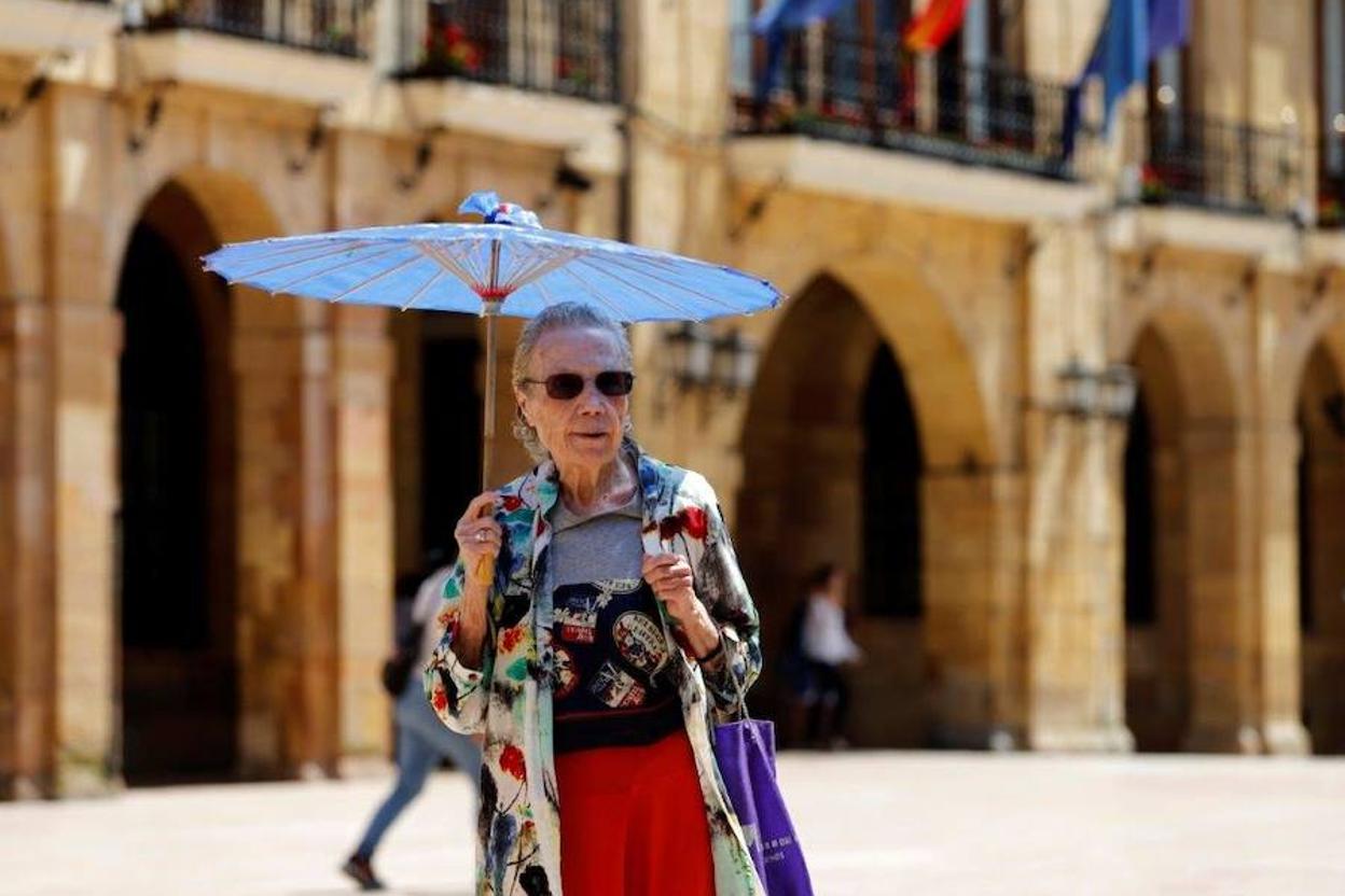 Una mujer se protege del sol con una sombrilla en Oviedo. 