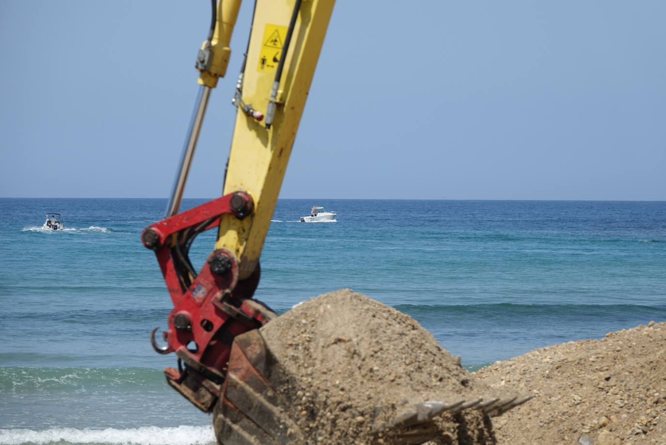 Una excavadora abre un canal en la playa de Santa Marina para intentar facilitar el posterior arrastre en pleamar del barco varado