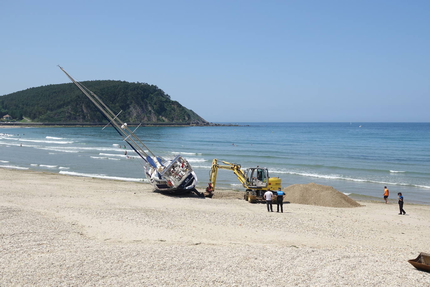 Una excavadora abre un canal en la playa de Santa Marina para intentar facilitar el posterior arrastre en pleamar del barco varado