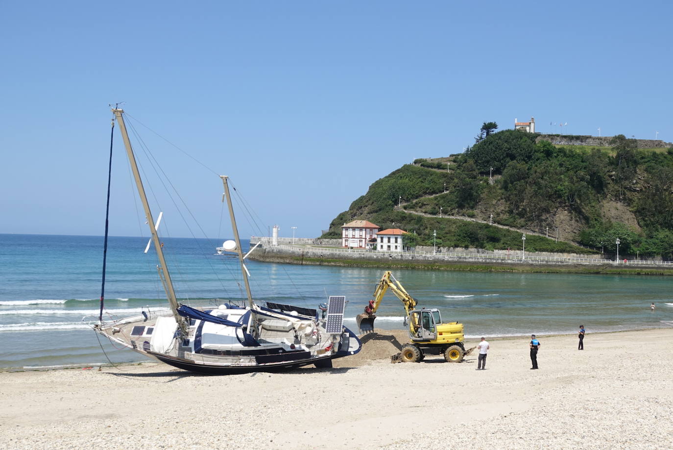 Una excavadora abre un canal en la playa de Santa Marina para intentar facilitar el posterior arrastre en pleamar del barco varado