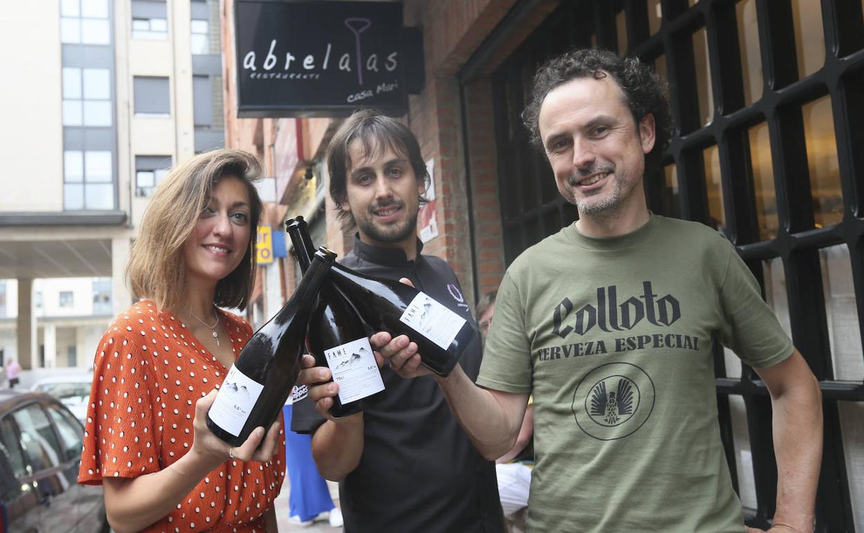 Aida Riesgo, Borja Alcázar y Diego Cotoya, con tres botellas de Fame, en la puerta del Abrelatas 