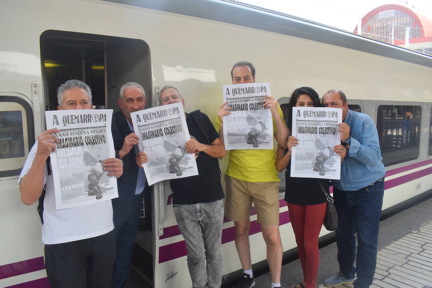 Organizadores y escritores muestran el diario oficial de la Semana Negra antes de iniciar el viaje a Gijón.