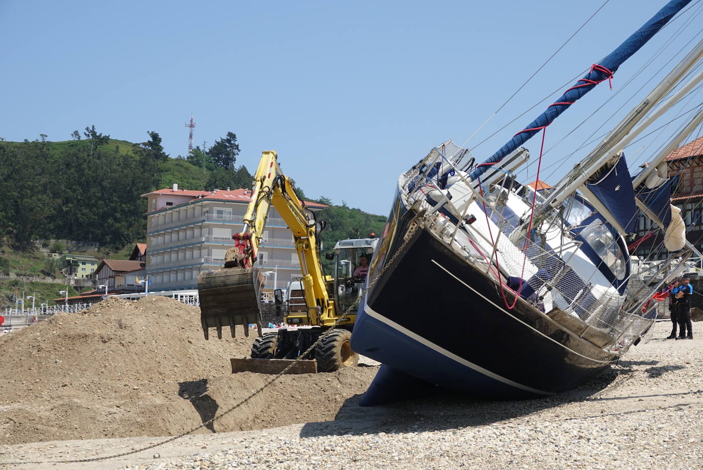 Una excavadora abre un canal en la playa de Santa Marina para intentar facilitar el posterior arrastre en pleamar del barco varado