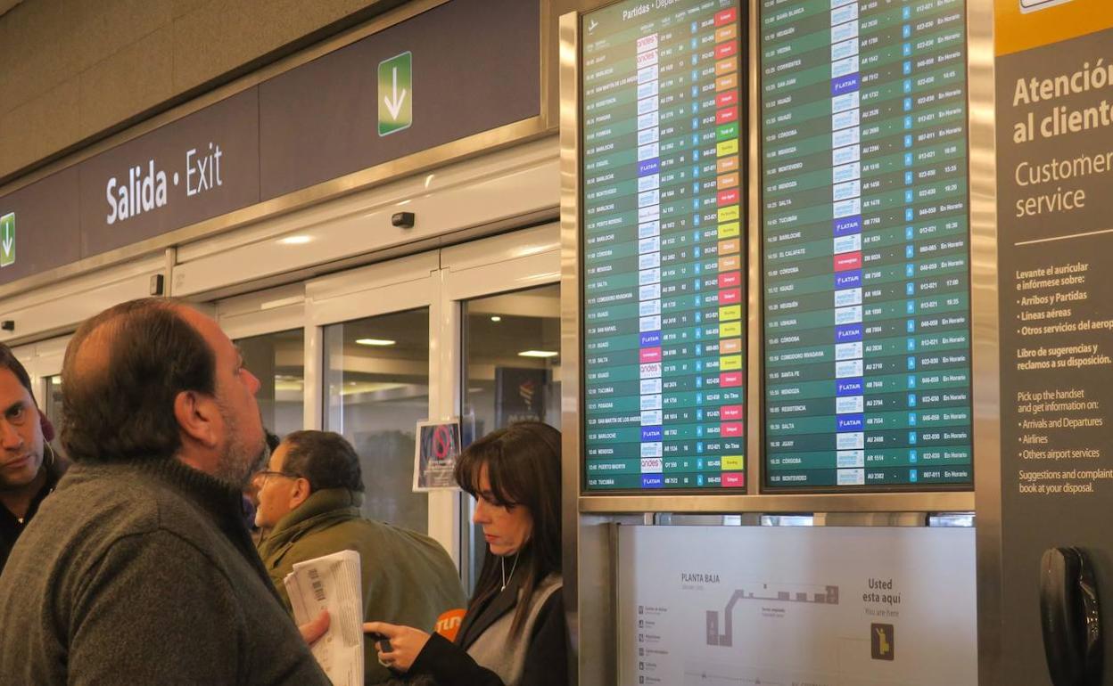 Usuarios de aeropuerto observan las pantallas de información. 
