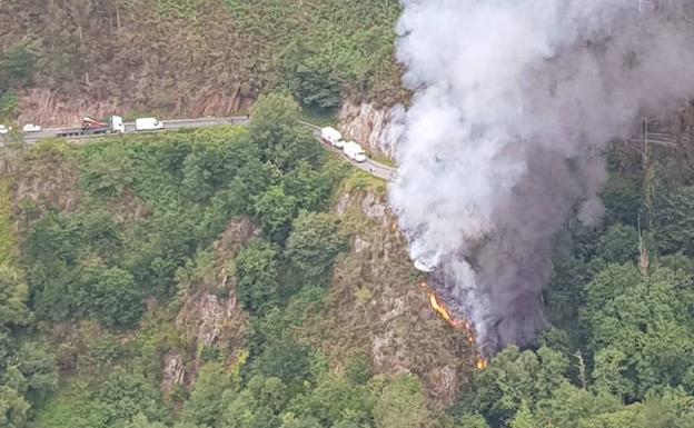 Imagen principal - Incendio declarado en el lugar del accidente. Abajo, el camión accidentado y los bomberos evacuando el cadáver.