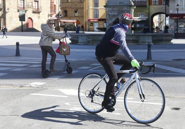 Un ciclista y una mujer en patinete eléctrico discuten en pleno carril bici en la calle Muelle de Oriente. 